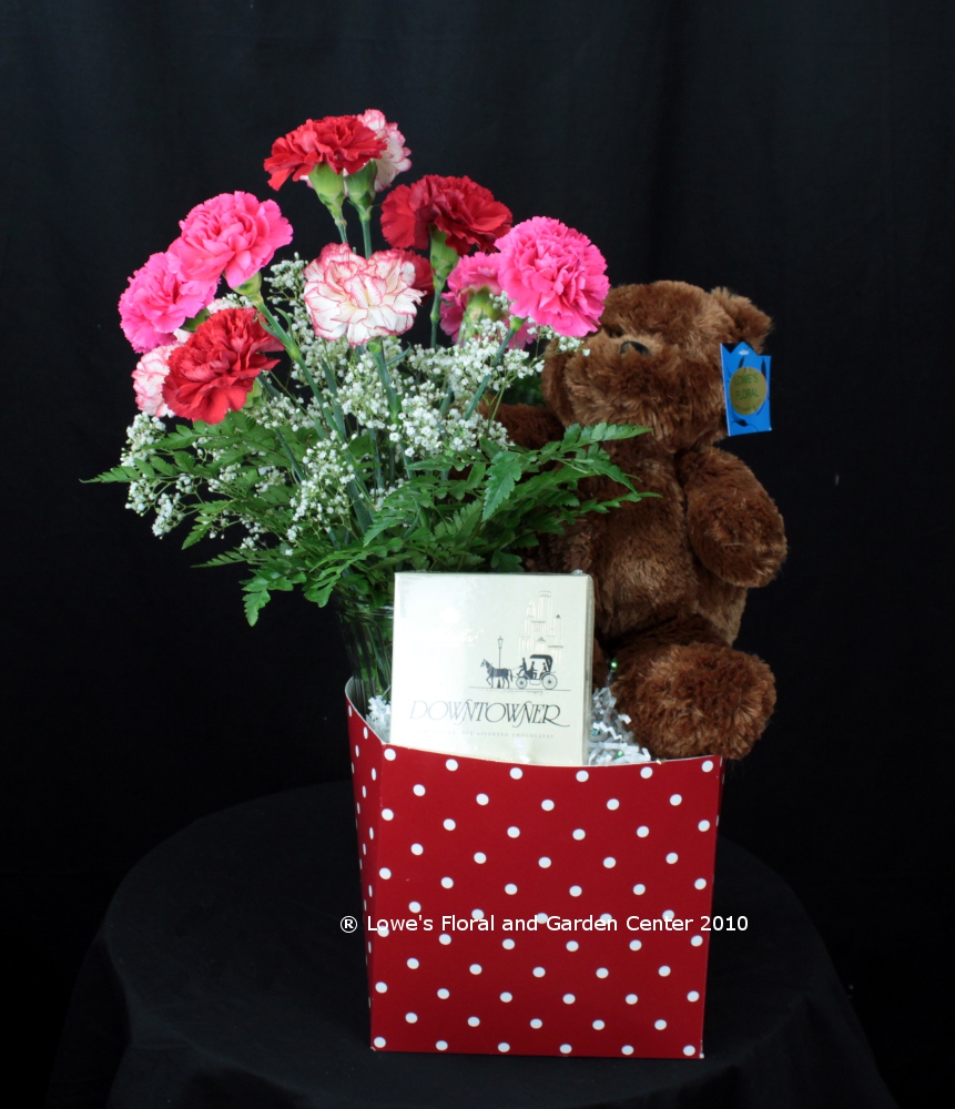 This unique gift creation features a dozen Valentine's carnations along with a plush teddy bear and gourmet chocolates.  